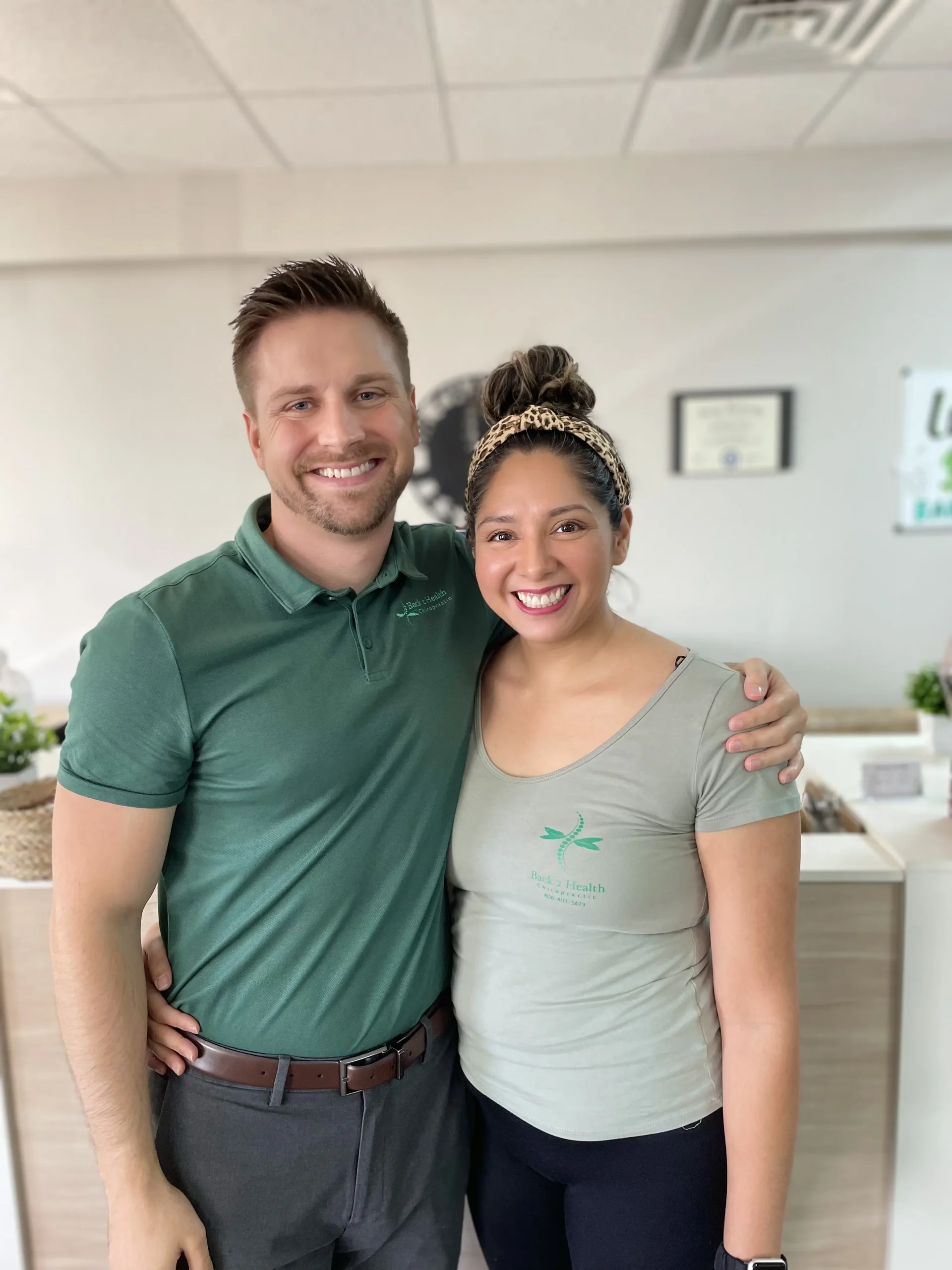 Portrait of Dr. Brett Chavez, smiling with arms crossed, wearing a green Back 2 Health polo